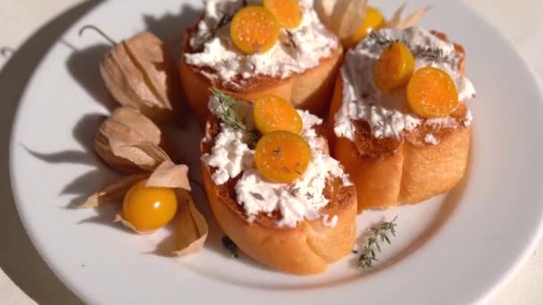 Ricotta bruschetta with cheese and Physalis fruits on a white plate — 图库视频影像