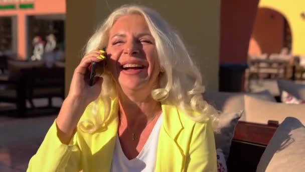 Kobieta w kawiarni rozmawia przez telefon i uśmiecha się — Wideo stockowe