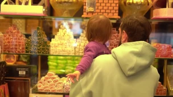 Kleines Mädchen sucht sich mit Papa im Süßwarenladen Süßigkeiten aus — Stockvideo
