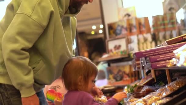 Niña está eligiendo dulces con papá en la tienda de dulces — Vídeo de stock