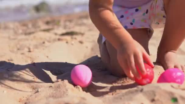 Mutlu kız sahilde paskalya yumurtalarıyla oynuyor. — Stok video