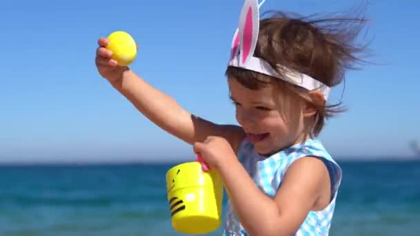 Šťastné dívky hrají s velikonočními vejci na pláži — Stock video