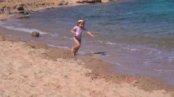 快乐的女孩，长着小兔子的耳朵在海滩上奔跑 — 图库视频影像