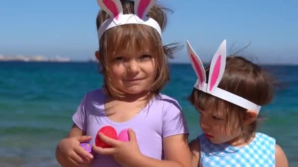 Dos niñas jugando con huevos de Pascua en la playa — Vídeos de Stock