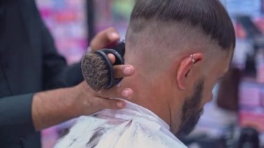 Berber, adamın saçını makasıyla kesiyor.