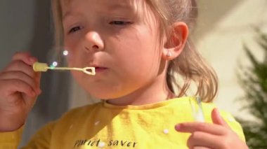 Küçük kız yazın dışarıda sabun köpüğü üflüyor.