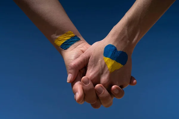 Ukrayna bayrağıyla boyanmış el ele tutuşan kadınlar