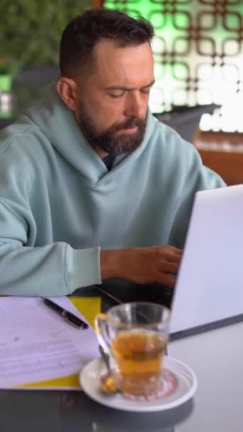 Homme buvant du thé et utilisant un ordinateur portable dans le café. — Video