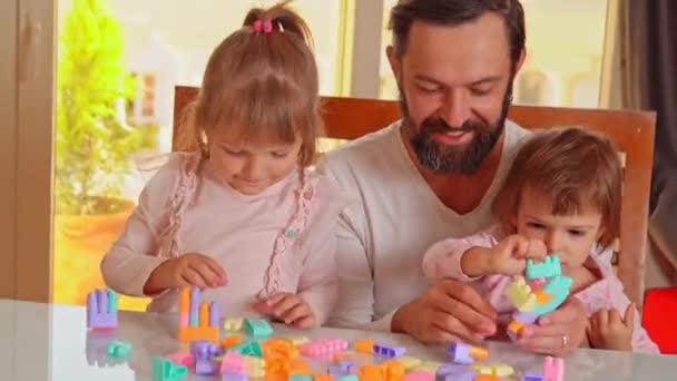 爸爸和他的两个女儿在家里玩构造游戏 — 图库视频影像