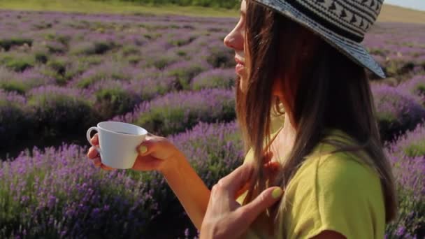 Woman with a cup of tea in her hand enjoys the view of the lavander field. — Stock Video