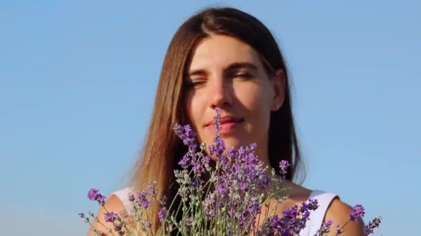 Nahaufnahme einer glücklich lächelnden Frau, die Lavendelstrauß riecht — Stockvideo