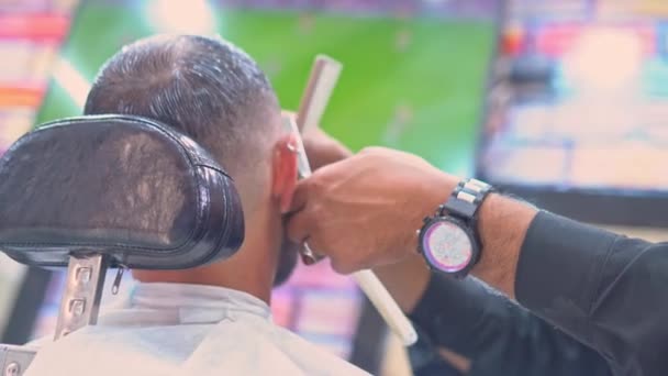 Hombre viendo el partido de fútbol en una barbería — Vídeo de stock