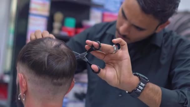 Barber cuts mans hair with scissors in a barbershop — Stock Video