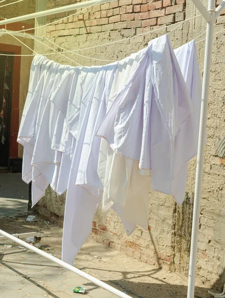stock image Clean bedsheet hanging on a clothesline at the street. 