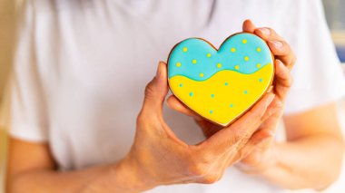 Kadın elinde Ukrayna bayrağı renginde kalp şeklinde zencefilli kurabiye tutuyor.