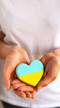 Kadın elinde Ukrayna bayrağı renginde kalp şeklinde zencefilli kurabiye tutuyor.