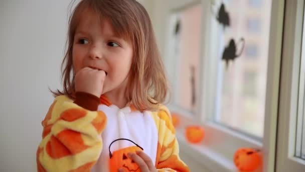 Szczęśliwa Dziewczyna Żyrafie Kigurumi Jedząca Cukierki Jasnopomarańczowego Kosza Dynią Jesienne — Wideo stockowe