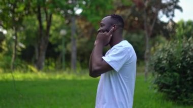 Parktaki seksi Afrikalı Amerikalı adam hava podları ve dansla müzik dinliyor. Sağlıklı yaşam tarzı.