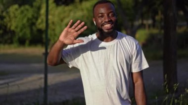 Genç Afro-Amerikan erkeği el sallayarak arkadaşını selamlıyor. Park 'tan görüntülü konuşma yapıyor, dışarıdaki sanal konferans, webcam görüntüsü...