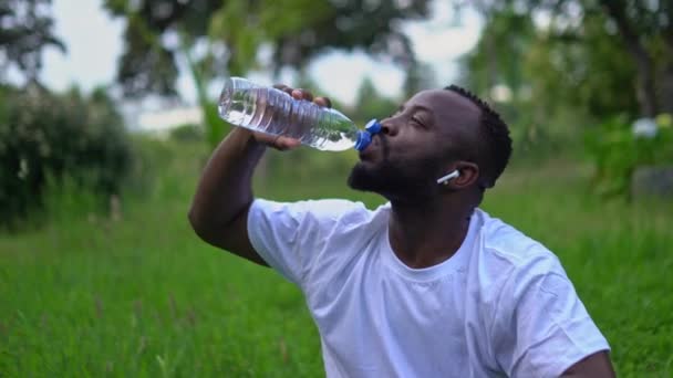 Hombre Afroamericano Adulto Joven Parque Bebiendo Agua Una Botella Mirando — Vídeos de Stock
