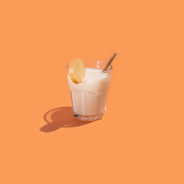 Glass with potato milk cocktail on beige background, creative minimalism and healthy food concept