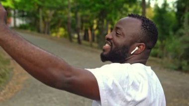 Parktaki akıllı telefonlu mutlu Afro-Amerikan koşucu. Sağlıklı yaşam tarzı.