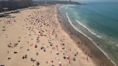 Ünlü Matosinhos Sahili 'nin kıyısında, renkli güneş şemsiyeleri ve yazın tadını çıkaran insanları gösteren destansı uçan dalgaların görüntüleri. Portekiz