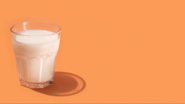 Glass with milk on beige background, creative minimalism and healthy food concept