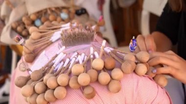 Bobbin lace handcrafting. Close-up of female hands braiding threads to make a pattern. Using threads and bobbins and needles according to the pattern.