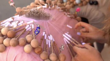 Bobbin lace handcrafting. Close-up of female hands braiding threads to make a pattern. Using threads and bobbins and needles according to the pattern.