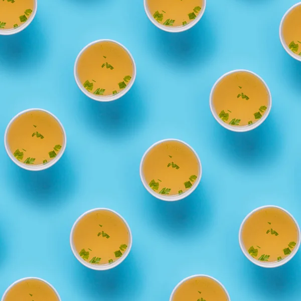 A Chicken broth soup in takeaway cup pattern on blue background
