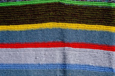 Örgü kumaş yüzeyinde farklı renkte çizgiler var. Tekstil retro halılar ya da halılar. Kumaşın dokusu çizgilerin geometrisiyle bir kombinasyondur..