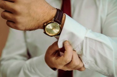 İş adamı kol saatini kontrol ediyor, saati eline alıyor, damat düğün töreninden önce hazırlanıyor.