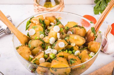 Bahar soğanlı patates salatası, maydanoz ve zeytinyağı, sarımsak ve sirke sosu cam kasede.