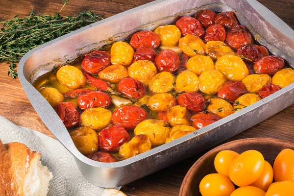 烤樱桃西红柿配大蒜 百里香和胡椒配橄榄油在烤盘里 法国自制西红柿 图库照片