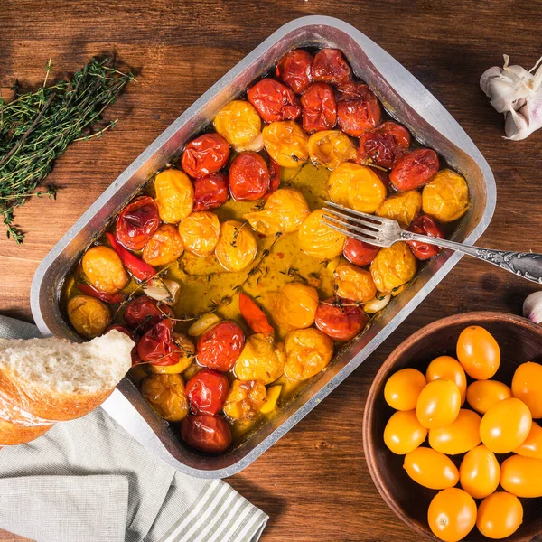 ガーリック タイム コショウで焼きチェリートマトとオリーブオイルをベーキングシートで調理 フランスの自家製トマトのコンフィ トップビューを作る ストック画像