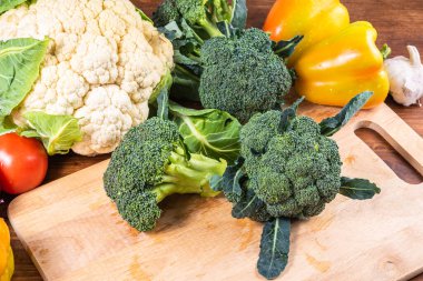 Tahta kesme tahtasındaki brokoli parçaları sebzelerin arka planına yakın plan.