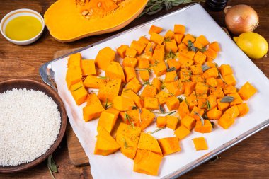 Balkabaklı risotto yapıyorum. İçindekiler: Tahtada doğranmış balkabağı parçaları, çiğ pirinç, soğan ve yakınlarda balkabağı püresi..