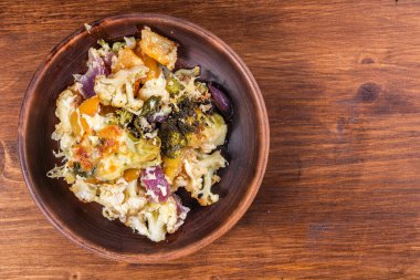 Baked vegetables with cheese - cauliflower, broccoli and peppers in a plate, top view, copy space.