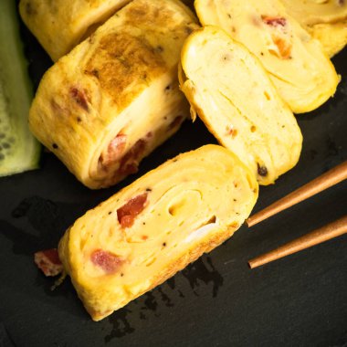 Tamagoyaki on a dark background with chopsticks - Japanese omelet, close-up