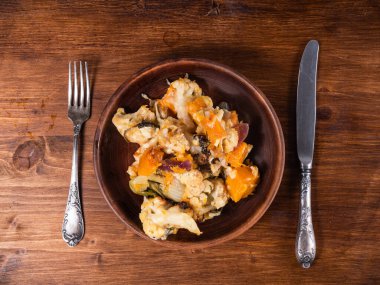 Portion of vegetables baked with cheese with pumpkin on a plate, top view