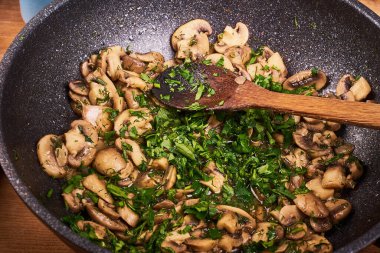 Büyük bir tavada maydanozlu kızarmış şampiyon mantarı.