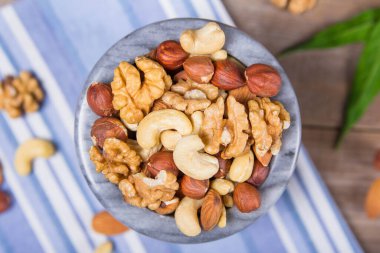 Kabuklu badem, ceviz ve fındık dolu mermer kase.