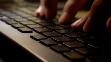 Typing on keyboard at night, close-up of man hands