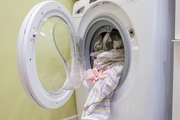 Çamaşır makinesinde kirli çamaşırlar. Çizgili yatak, ev işleri, çamaşır makinesinde çamaşır yıkamak için hazır..