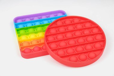 Gökkuşağı Meydanı ve Kırmızı Fidget Oyuncakları beyaz arka planda. Pop Bubble 'ı it. Popüler rahatlatıcı silikon stres giderici oyuncak. Bakış açısıyla bak.