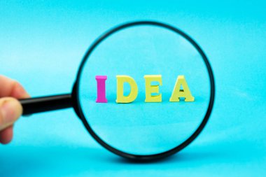 Açık mavi arka planda büyüteç altındaki ahşap parlak harflerden türetilmiş bir kelime. Yaratıcı kavram: yeni fikirler aramak, beyin fırtınası, yaratıcı aktivite.