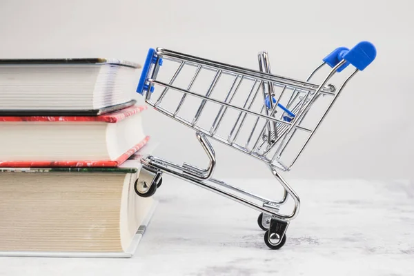 ショッピングカートは本の山の上にあります 紙本の販売 教育文学の購入 教育用印刷物 — ストック写真