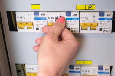 Kadın dairesinin elektrik panelinin düğmesini kapatıyor. Evde sigortalı ve devre kesicili evler için izole edilmiş telefon santrali. Moskova, Rusya - 11.24.2021