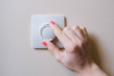 Bir kadının eli loş bir kolla ışıklandırmayı ayarlar. Elektrik gücünü değiştirmek için tasarlanmış elektronik bir cihaz. Yanardöner lambalar veya LED 'ler tarafından yayılan ışığın parlaklığını ayarlamak için kullanılır.